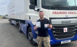 Gary celebrating his Category C+E 3b test pass at MT Training Services Kidderminster, standing next to a DAF articulated training lorry