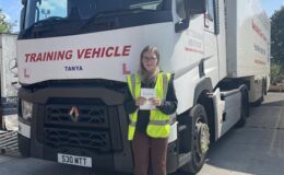 Pippa proudly holding her pass certificate beside MT Training Services' articulated HGV training vehicle in Manchester