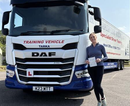 Carina celebrating her HGV CE 3b test pass at MT Training Services Bristol, standing next to a DAF articulated training lorry