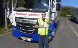 Michael holding his Cat C 3a test pass certificate in front of an MT Training HGV at the Plymouth training centre