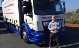 Trainee driver standing in front of a Cat C training lorry at MT Training Services Taunton after passing HGV test on a clear day