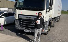 Arslan celebrates passing his CE 3b HGV driving test at the Birmingham Training Centre in front of a DAF lorry.