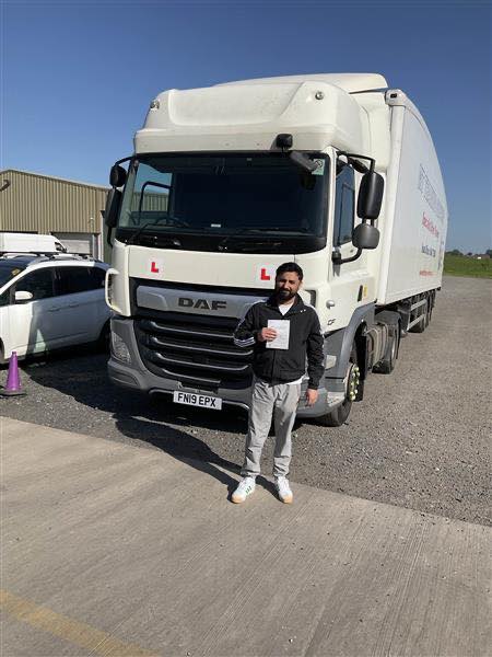 Arslan celebrates passing his CE 3b HGV driving test at the Birmingham Training Centre in front of a DAF lorry.
